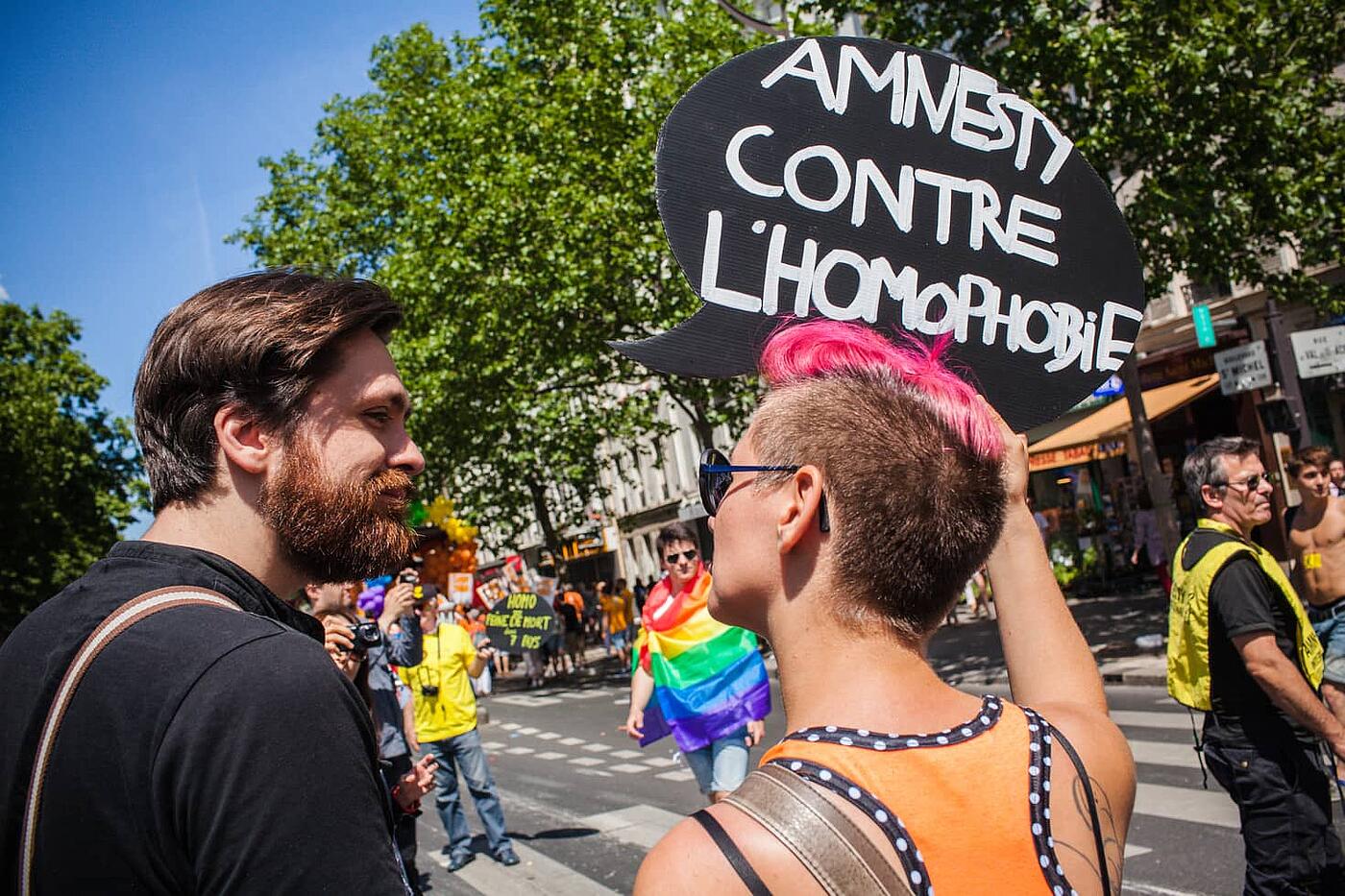 Dos personas en la Marcha del Orgullo en París portan una pancarta que pone "Amnesty contre l'homophobie"